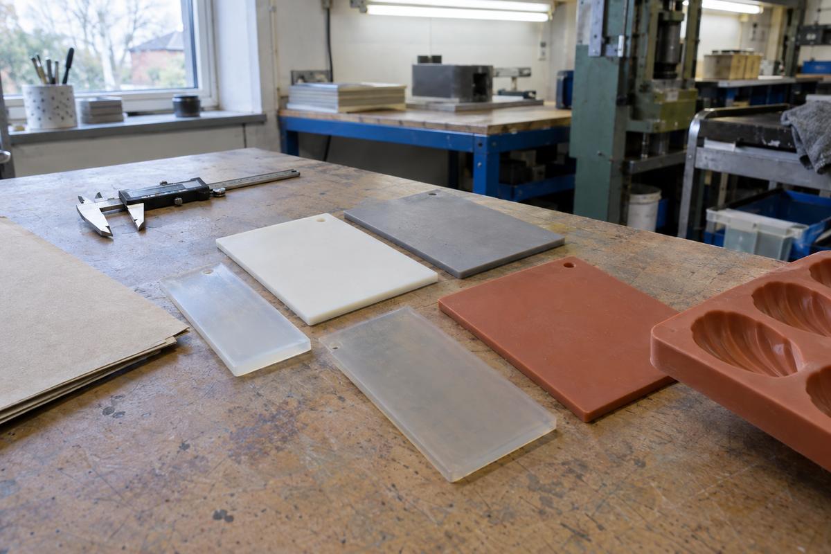 Silicone sample plaques and paperwork on a workshop bench