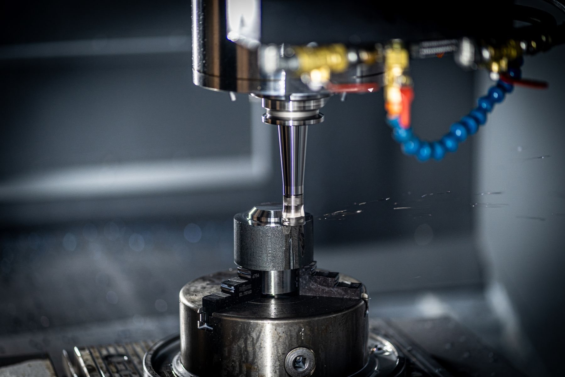 CNC spindle and cutter with coolant on a vertical machining centre.