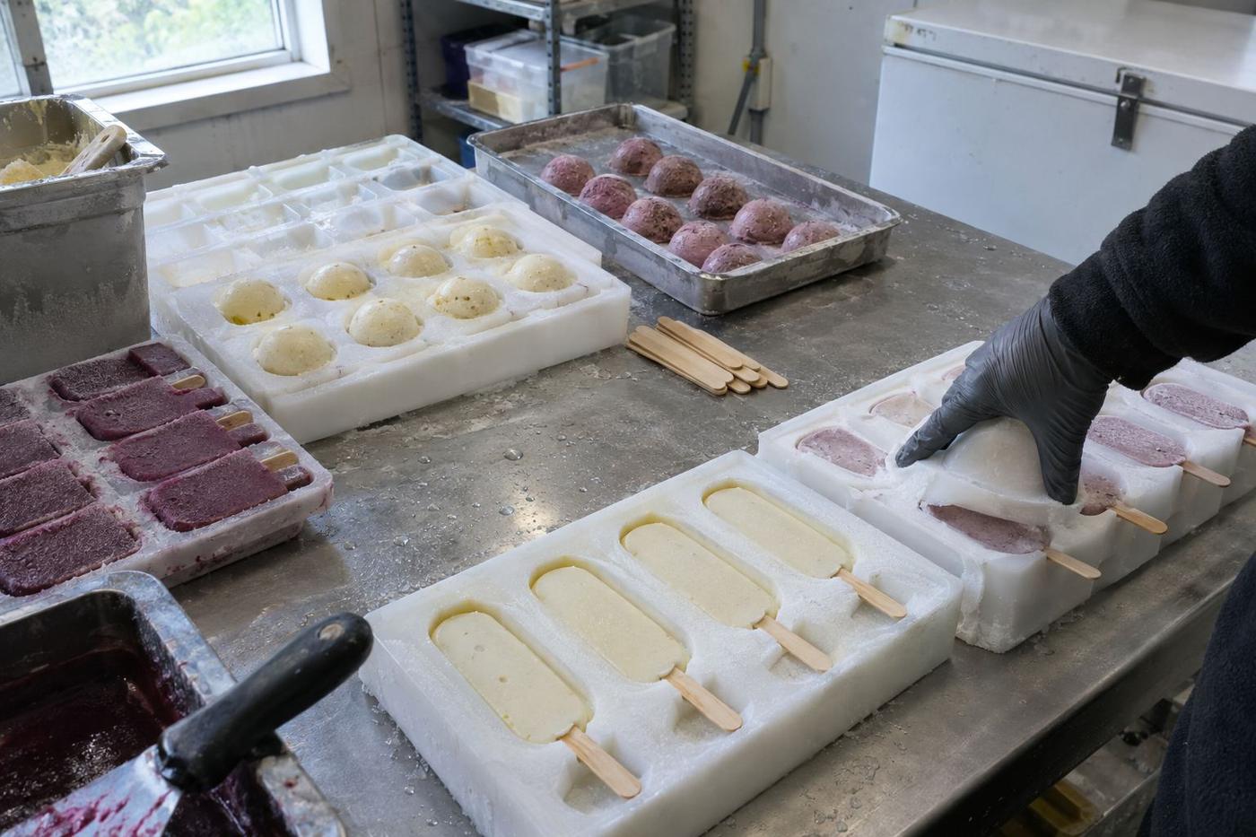 Frozen dessert moulds with sticks on a chilled metal table